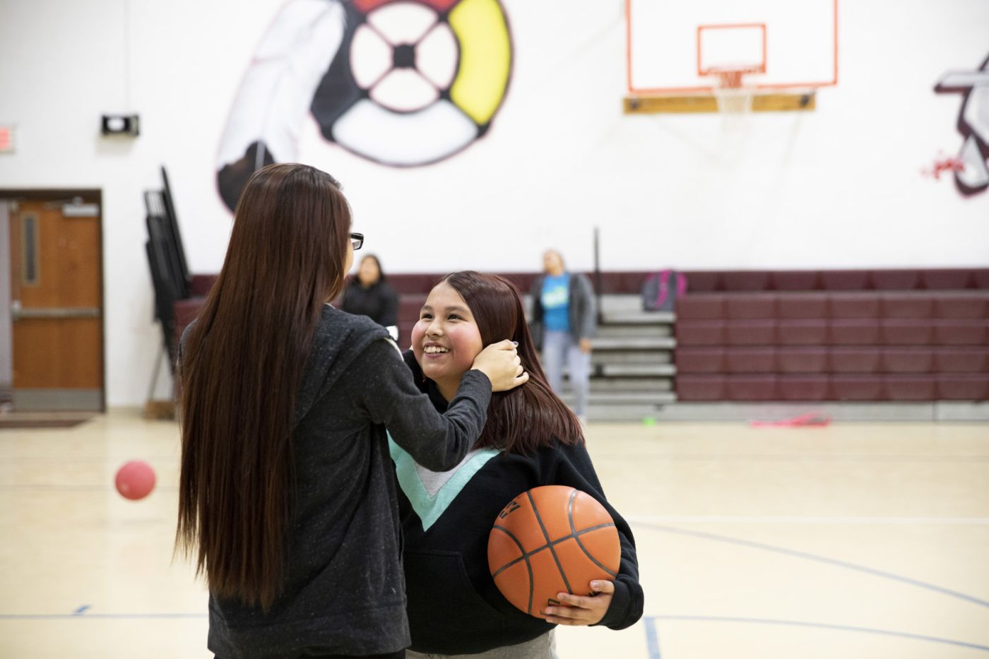 Two young women embrace on the basketball court