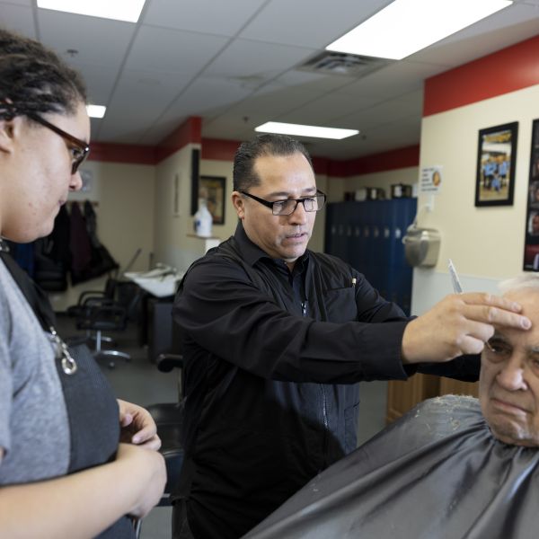 man teaches barber how to cut hair