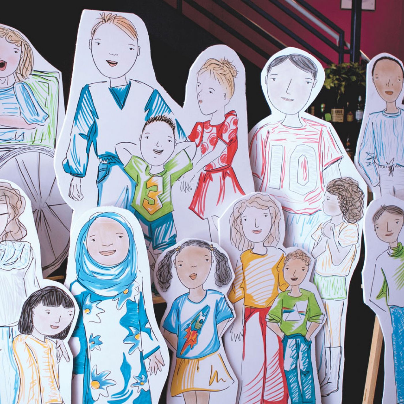 A group of life-sized cardboard cutouts of illustrated diverse children.