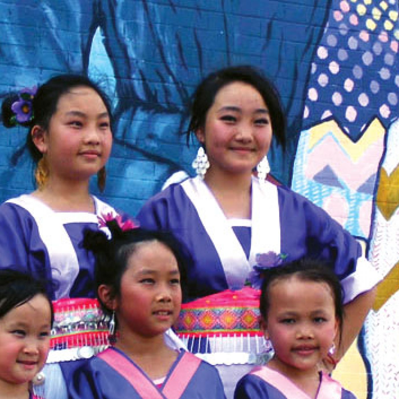 Young Hmong women in front of mural