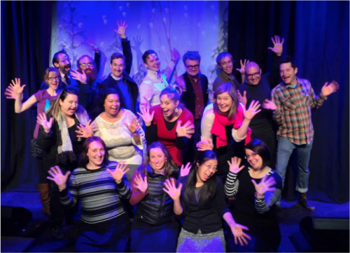 Photo of Springboard staff and board standing on a stage flashing their jazz hands.